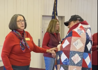 Chris Wyman, a Navy veteran, is wrapped in a Quilt of Valor. At left is Carol Johnson, leader of the Sussex County Quilters. (Photos provided)