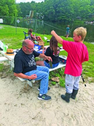 Thomas Cummings, 9, of Sussex waits for the sunfish he caught to be weighed and measured by Warren Wisse, president of the Wantage Recreation and Parks Advisory Committee.