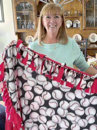 Joan Kirchmer of Sussex holds a baseball-themed fleece blanket for abused children at Ginnie’s House.
