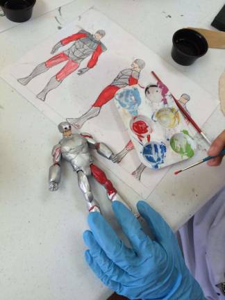 A student paints an action figure.