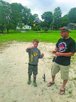 Jaxon Babcock, 8, of Wantage holds up a yellow perch. His father, Curt, is at right. Jaxon caught the largest fish among children age 10 and younger.