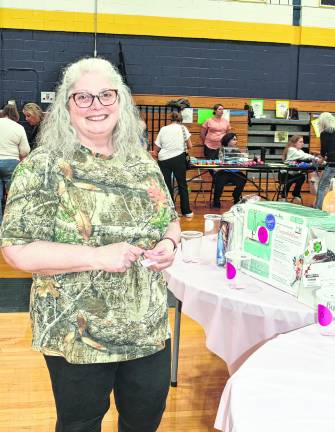 <b>Cathy Havens of Wantage stands in front of a table.</b>