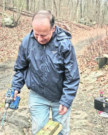 <b>Martin Grossman, president of the Paulinskill Valley Trail Committee, using old wood as a template before drilling into replacement pieces as part of ongoing trail maintenance. </b>