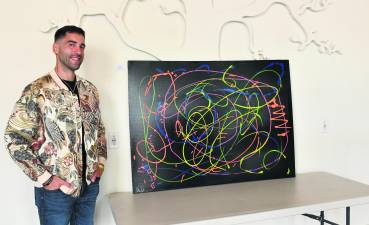 <b>Brian Cheda of Andover stands next to his painting, Pathways to Recovery.</b>