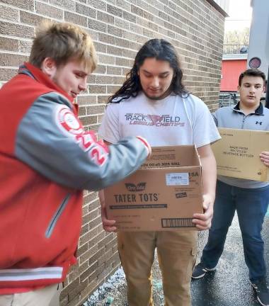 Paul Hajtobik, a senior, makes sure Robert places the donations inside the box before he places it onto the bus.