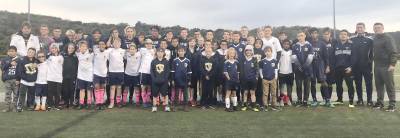 Youth participants gather with high school team members and coaches for a group picture.