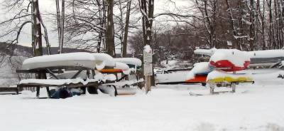 Snow covered boats that are forced to hibernate until spring.