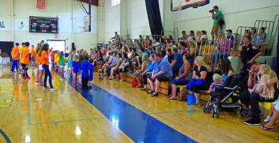 The children are shown lined up to share what they have learned with family members in the audience.