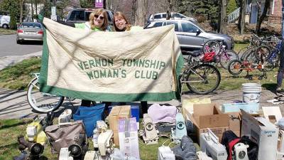 International Committee chair Karen Rothstadt (left) and communications chair Lisa Mills display their club banner with many of the 58 sewing machines collected during the 2019 project (Photo provided)
