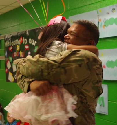 PHOTO BY CHRIS WYMAN Army Sergeant First Class Roland Tajalle and his daughter RaiþÄôAna, 5, embrace each other in the main hall of Walnut Ridge Primary School on Sept. 16.