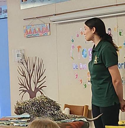 A female porcupine named Charlie stands on a table in the library as Kim Diez of Eyes of the Wild talks about its quills.