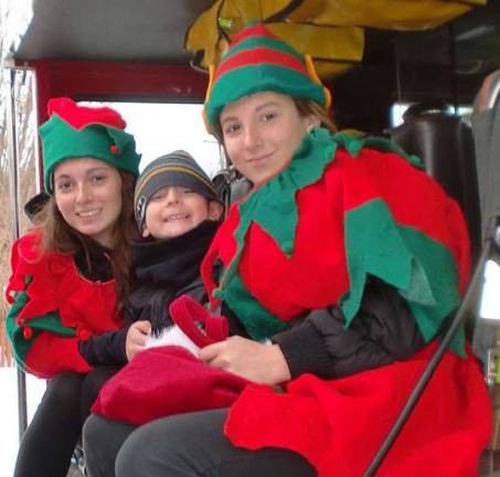 Elf helpers (Cassidy and Emily Heiden) keep their brother, Brian, warm on the fire truck.