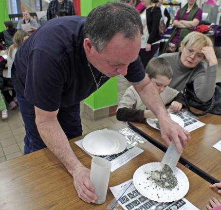 Paleontologist John Miller is shown pouring the material onto plates for the children to sift through.
