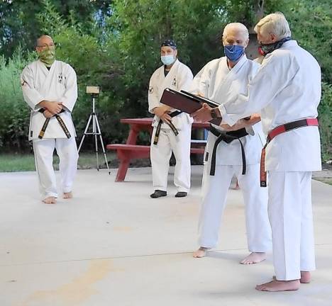 From right, Sensei Tom Shull receives his seventh degree black belt from Sensei Chuck Ercolano.