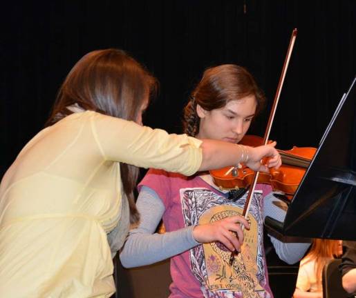 VTHS Orchestra Senior Sarah McGuire (left) gives 8th grader Maya Rakoczy a few pointersduring rehearsal.