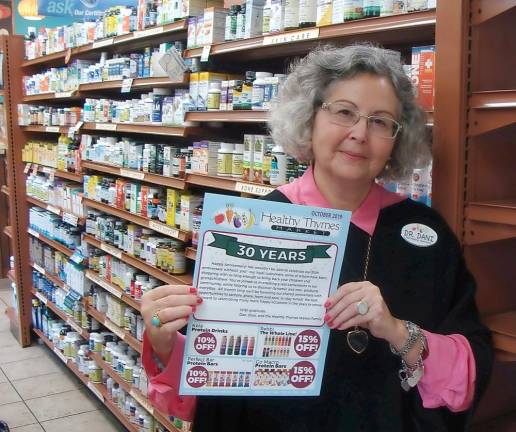 Dr. Dani Segal displays the 30th anniversary sale flyer at Healthy Thymes Market.