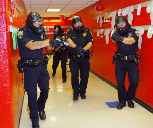 PHOTO BY CHRIS WYMAN With weapons drawn, four Vernon Township police officers walk down the main hall at Walnut Ridge Primary School, during an Aug. 1 drill, searching for three active shooters in the school and two hostages being held in a classroom.