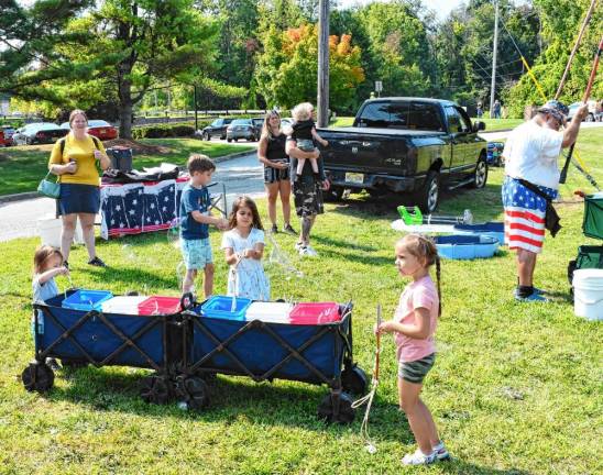 <b>Children use poles to draw out the bubbles.</b>