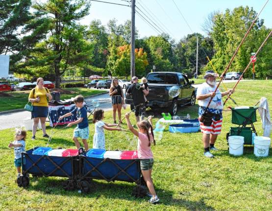 <b>Children use poles to draw out the bubbles.</b>