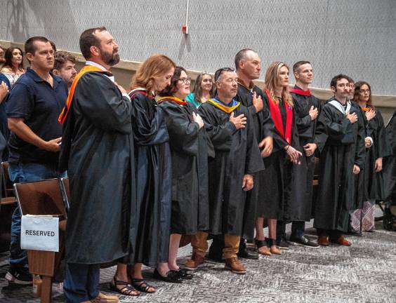 Faculty members recite the Pledge of Allegiance.