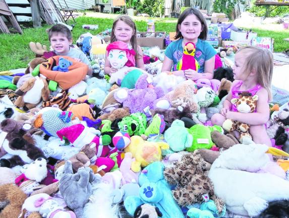 <b>Children sit among stuffed animals.</b>