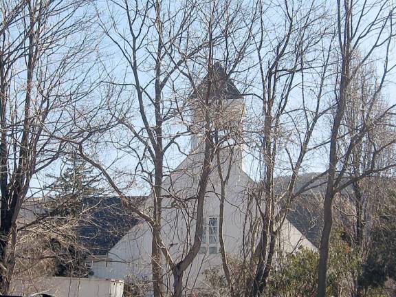 The steeple of the former St. Thomas Church looms through the trees.