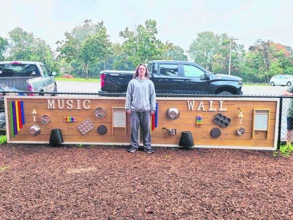 Matthew Okken stands by the Music Sensory Wall that he built at Walnut Ridge Elementary School.