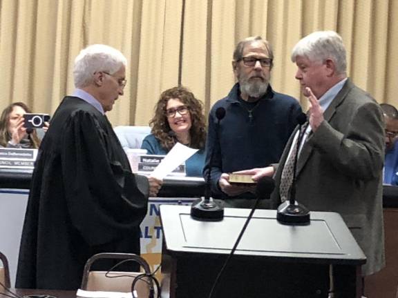 William Higgins, right, takes the oath of office as a new member of the Township Council. The former school board member was elected to the council Nov. 7.