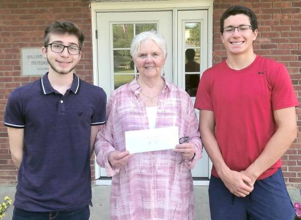 Squire Nick Furnari and Notary Squire Riley Maldonado present a donation check to Sandy Mitchell of Project Help in front of the Sparta VFW building (Photo provided)