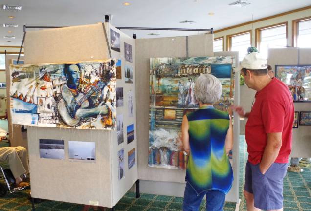 Visitors look at a series of paintings by Highland Lakes artist Dennis Dalelio.
