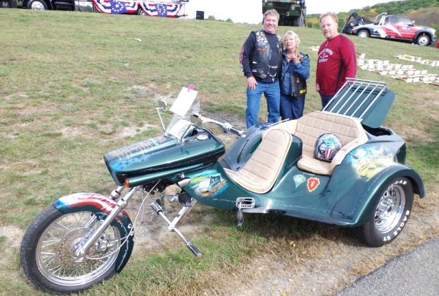 Owners of this trike, Joe and Rose Larochelle of Flemington stand with Wantage resident Art Frisbie, who is the artist who painted the Vietnam War-related scenes on the motorcycle. On the front fender are the names of ten men of the Army 25th Infantry who died in battle on February 14, 1969.
