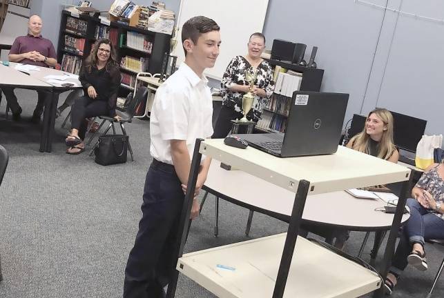 Nicolas Marchionda at the school board meeting, his teacher Valerie Reeth pictured behind him