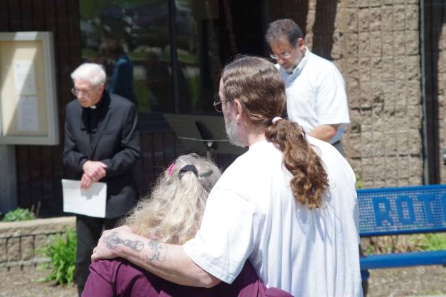 A couple listens to prayers being offered in front of the Vernon Municipal Building.