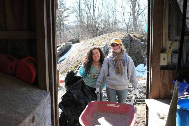 Misericordia University students Sarah Munley, left, and Courtney OMalley smile while tackling the chore of mucking the goat pen at the Mercy Farm in Benson, Vt., during a spring break service trip.