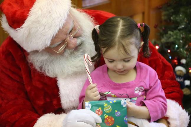 Santa gives Aubrie Strick of Wantage a goodie bag while listening to her wish list.