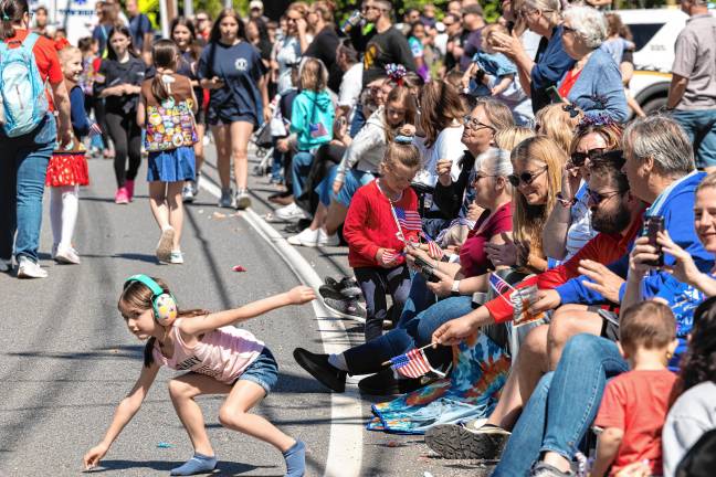 <b>A girl picks up candy tossed to the crowd.</b>