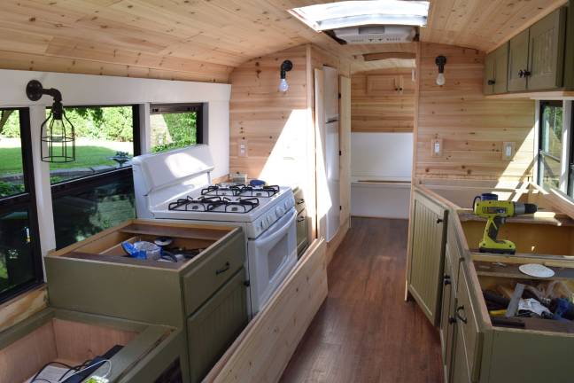 Photo by Erika Norton The inside of the &quot;skoolie&quot; features three couch/beds, a stove, a sink, cabinets, a full shower and a composting toilet.