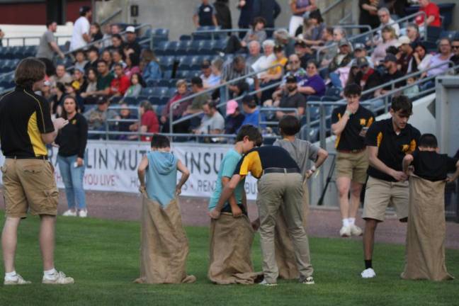 Children compete in potato sack races during a break in the game.