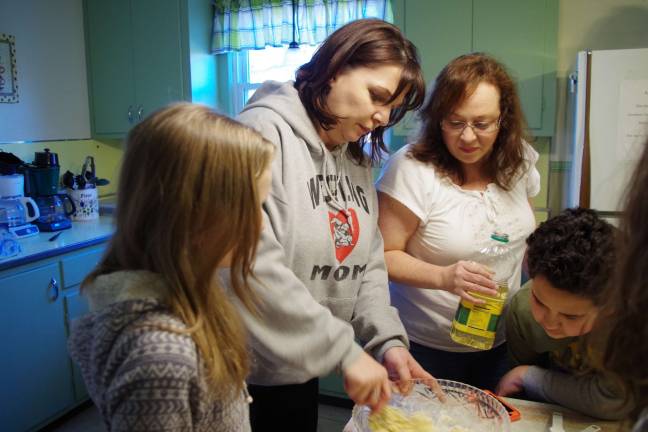 At center are youth group leaders Davida Schnebelen, left, and Lisa Ferruggia as they help prepare the banana bread for the church&#xfe;&#xc4;&#xf4;s food pantry.