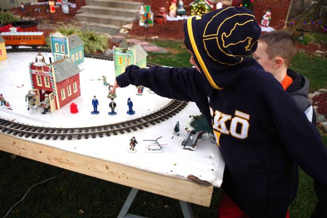 PHOTO BY CHRIS WYMAN Eli Convit, 6, shows his friend TJ Morgan, 5, that this train display and village are like the real thing as he points out the mayor as the character wearing a top hat at Bob Winter's train display on Dec. 6.