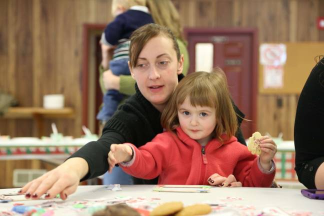 Amy and Layla Praschil of Wantage have a cookie and make a photo frame at the party.
