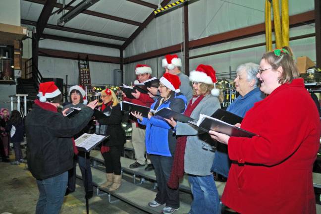 The Community Choral Society is led by director Danielle Kastner and is shown performing in the vehicle bays of the Vernon Township Fire Department.