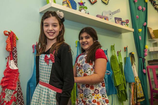 Gianna Shraga, 9, of Allamuch (left) gets her apron tied by Mia Rizzo, 10, of Sparta.