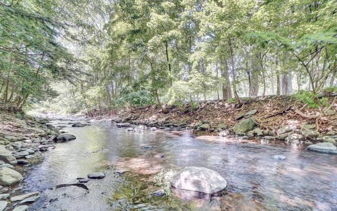 Upscale streamfront custom farmhouse offers space and more