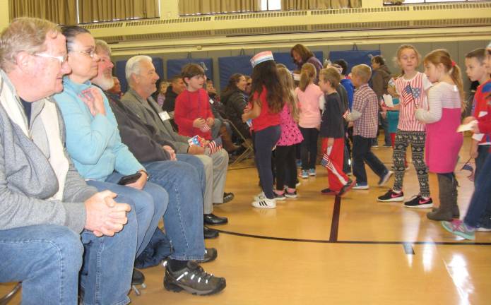 PHOTOS BY JANET REDYKECedar Mountain students give special red, white and blue gifts to veterans attending the Veterans Day program at the school.