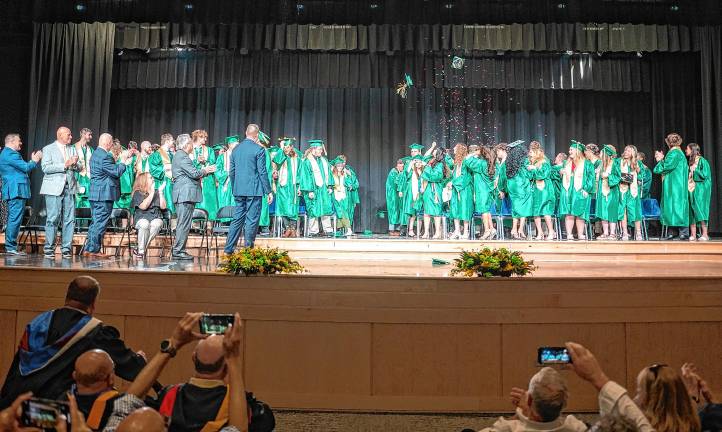 Caps and confetti fly through the air at the end of graduation.