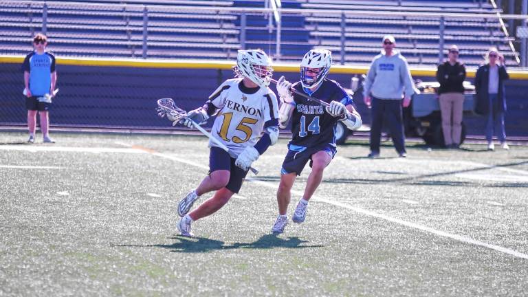 <b>Vernon's Andrew Geisen carries the ball with his crosse while covered by Sparta's Danny Westervelt in their game April 17. The Spartans won, 15-0. (Photos by</b> <b>George Leroy Hunter)</b>