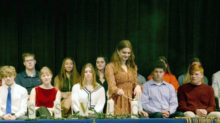 Vernon Township High School National Honor Society secretary Gabrielle Miller lights a candle during the induction ceremony.