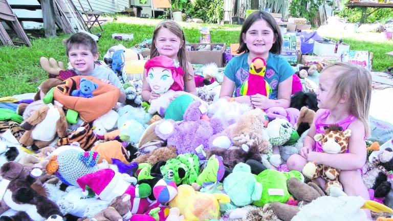 <b>Children sit among stuffed animals.</b>
