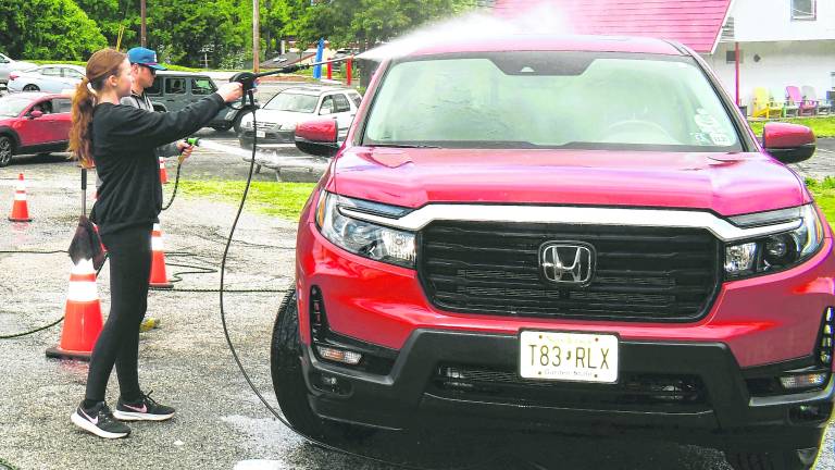 <b>Taylor Tittle of Vernon sprays down a car.</b>